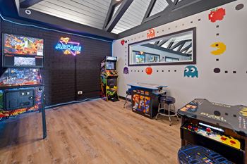 A room with a wooden floor and a wall with a neon sign that says "ARCADE".